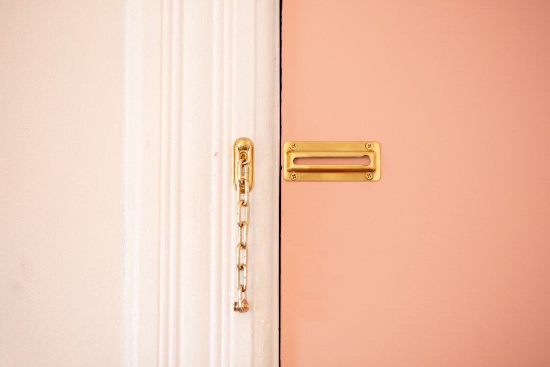Détail d'une chaîne de sécurité dorée sur une porte rose.