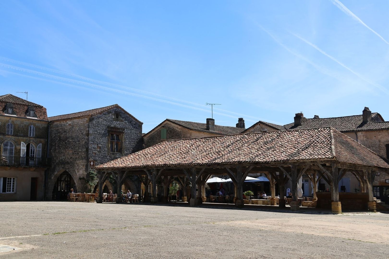 Place de village française bordée de maisons anciennes et d’une halle