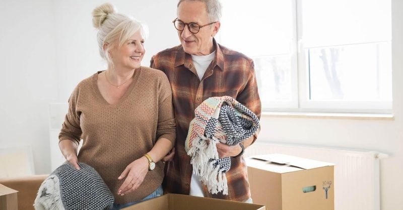 Couple âgé rangeant des couvertures dans des cartons de déménagement
